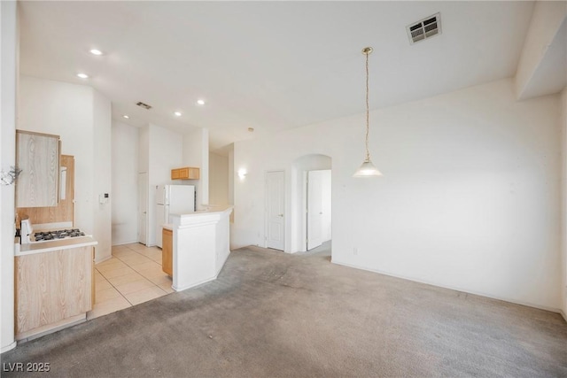 kitchen with light colored carpet, freestanding refrigerator, visible vents, and arched walkways