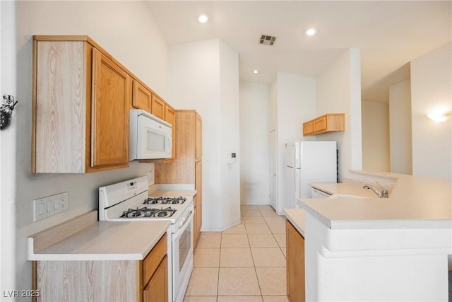 kitchen featuring light tile patterned floors, a peninsula, white appliances, and light countertops