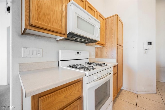 kitchen with white appliances, light tile patterned floors, baseboards, and light countertops