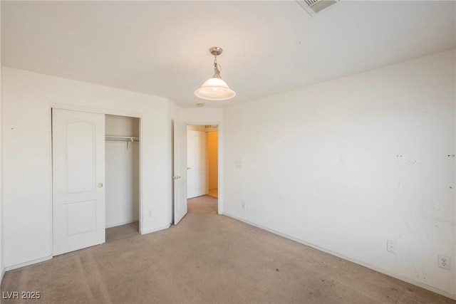 unfurnished bedroom with a closet, visible vents, and light colored carpet