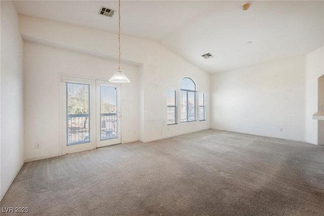 carpeted empty room featuring lofted ceiling and visible vents