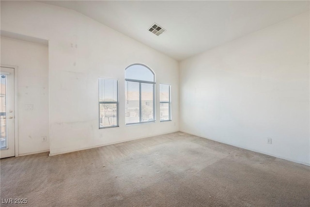 carpeted empty room with high vaulted ceiling and visible vents