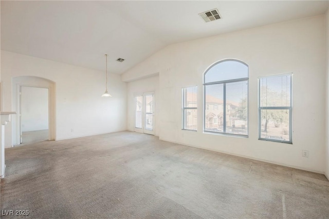 spare room featuring high vaulted ceiling, visible vents, arched walkways, and light colored carpet