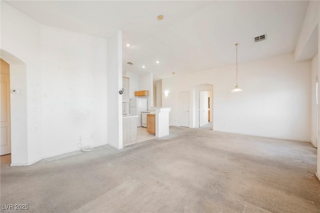 unfurnished living room featuring recessed lighting, visible vents, arched walkways, and light colored carpet