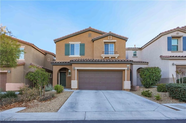 mediterranean / spanish home featuring concrete driveway, an attached garage, a tiled roof, and stucco siding