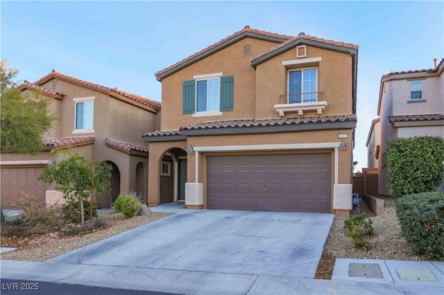 mediterranean / spanish house featuring a garage, concrete driveway, a tile roof, and stucco siding