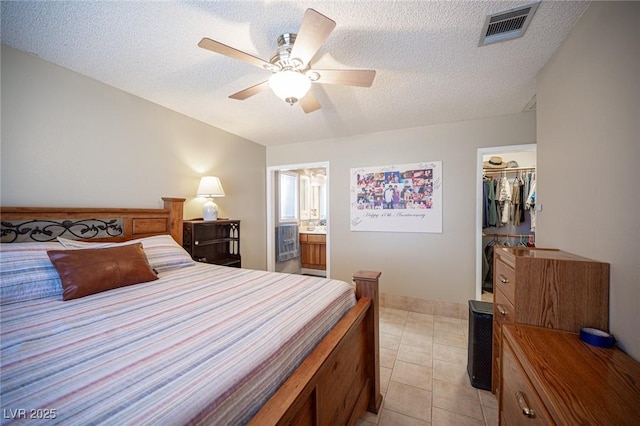 bedroom featuring visible vents, a spacious closet, a textured ceiling, and light tile patterned floors