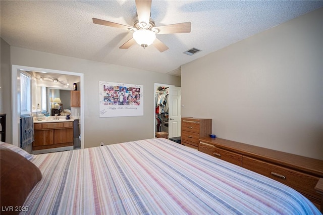 bedroom with a closet, visible vents, connected bathroom, ceiling fan, and a textured ceiling