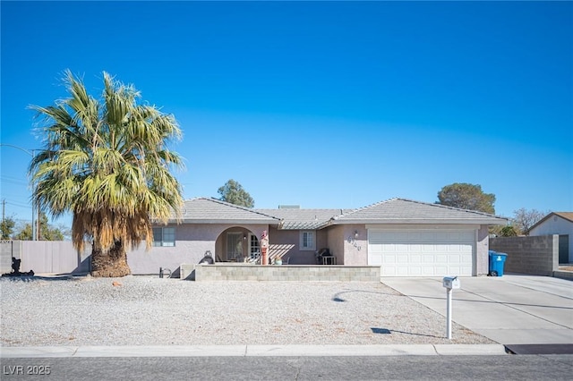 ranch-style home featuring an attached garage, driveway, fence, and stucco siding