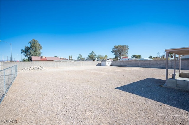 view of yard featuring a storage shed, a fenced backyard, and an outbuilding