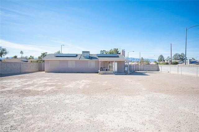 view of front of property featuring a fenced backyard and solar panels