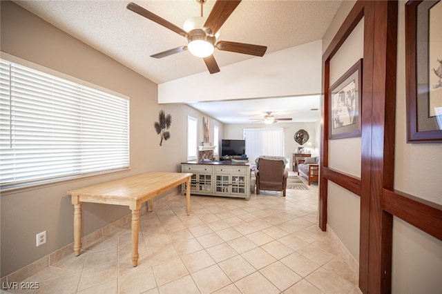 dining area featuring a ceiling fan, lofted ceiling, a textured ceiling, and light tile patterned floors