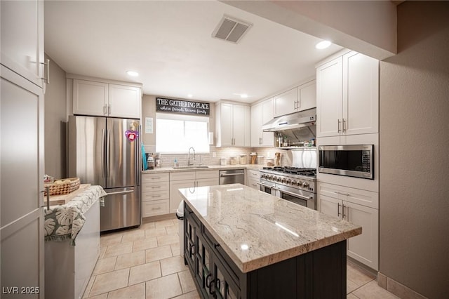 kitchen featuring under cabinet range hood, a kitchen island, visible vents, white cabinets, and appliances with stainless steel finishes