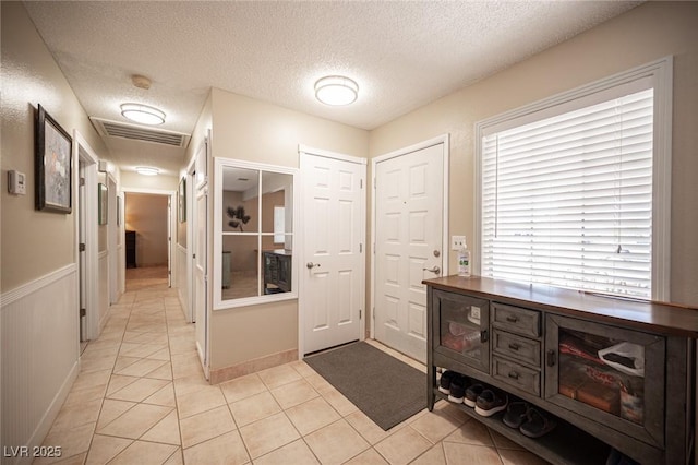 interior space featuring a textured ceiling, light tile patterned flooring, and visible vents