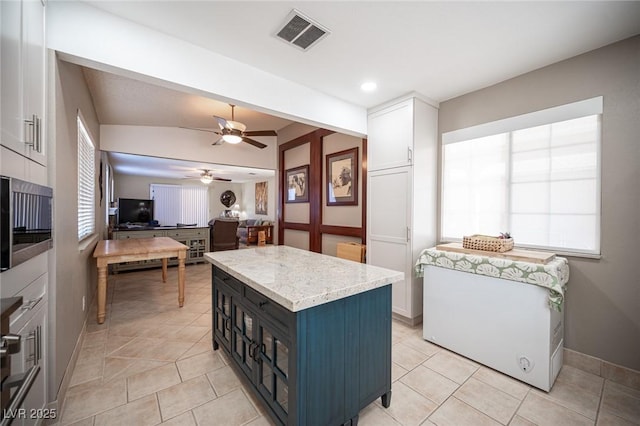 kitchen featuring white cabinets, visible vents, light countertops, and a center island