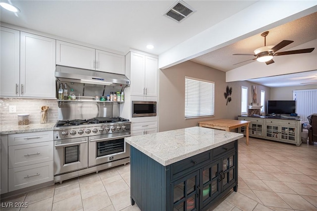 kitchen featuring under cabinet range hood, stainless steel appliances, white cabinetry, visible vents, and backsplash