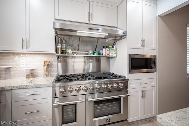 kitchen with stainless steel appliances, white cabinets, decorative backsplash, and light stone counters