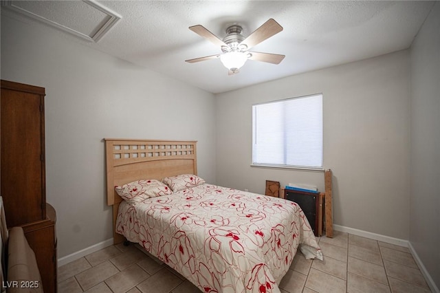 bedroom featuring light tile patterned floors, attic access, ceiling fan, a textured ceiling, and baseboards