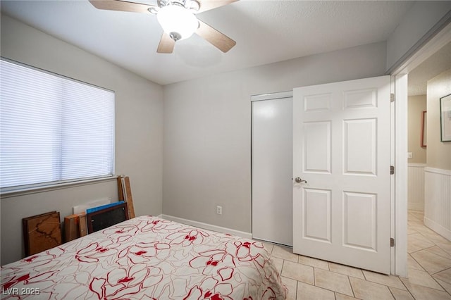 bedroom with light tile patterned floors, a textured ceiling, a ceiling fan, and a closet