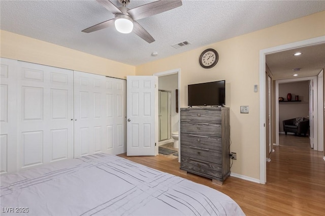 bedroom featuring a closet, visible vents, a textured ceiling, and wood finished floors