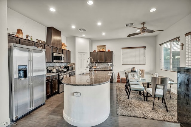 kitchen featuring dark stone counters, appliances with stainless steel finishes, visible vents, and dark brown cabinetry