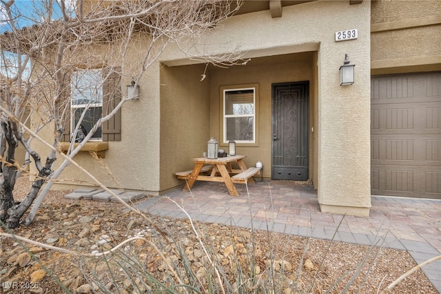 view of exterior entry featuring a garage and stucco siding