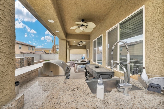 view of patio / terrace featuring area for grilling, a ceiling fan, a grill, fence, and a sink