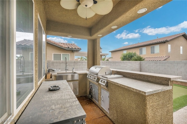 view of patio with area for grilling, a ceiling fan, a grill, a sink, and a fenced backyard