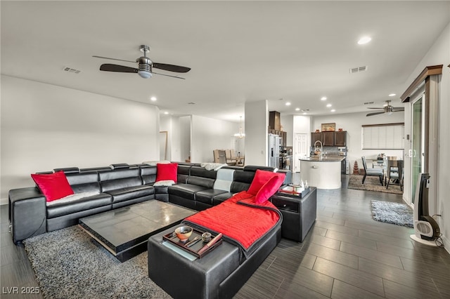 living room with ceiling fan with notable chandelier, visible vents, and recessed lighting