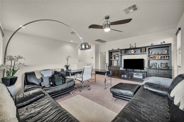 living area with light colored carpet, visible vents, and ceiling fan