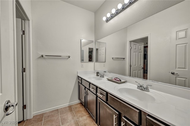 full bathroom with double vanity, a sink, and baseboards