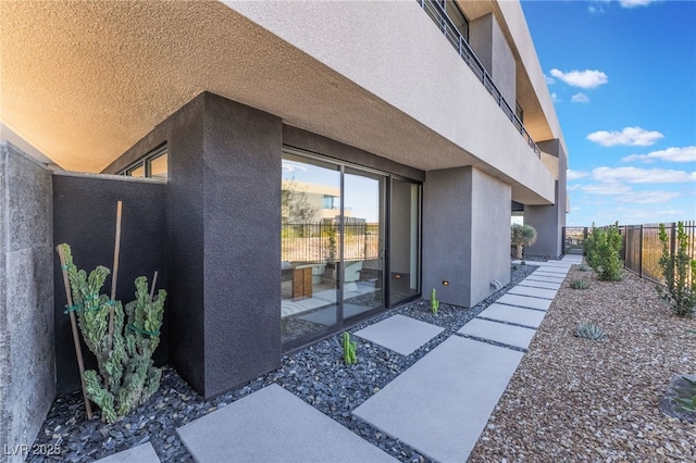 view of side of home with fence and stucco siding