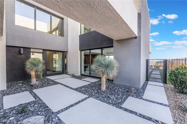 exterior space with a gate, fence, and stucco siding