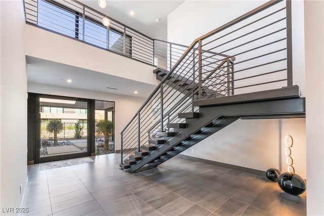 stairway featuring recessed lighting, tile patterned flooring, a towering ceiling, and baseboards