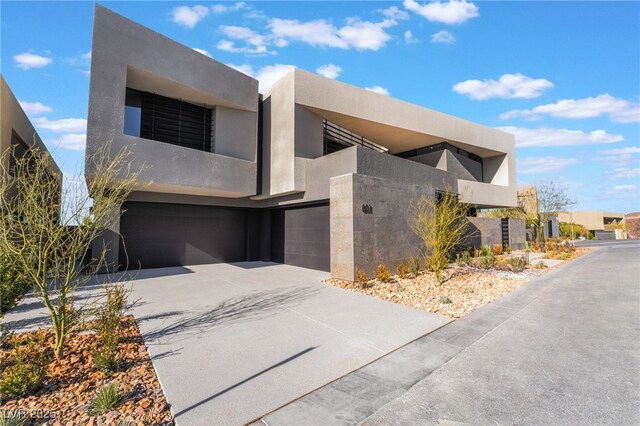 modern home featuring a garage, a balcony, stucco siding, and concrete driveway