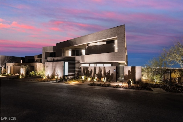 contemporary home with driveway, fence, and stucco siding