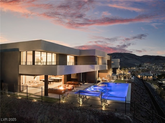 rear view of property featuring stucco siding, a patio, fence, a balcony, and a mountain view