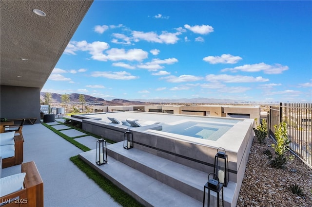 exterior space featuring an in ground hot tub, fence, and a mountain view