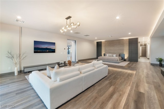 living room with a notable chandelier, visible vents, wood finished floors, and recessed lighting