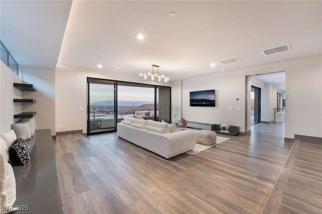 living area with recessed lighting, visible vents, an inviting chandelier, light wood-type flooring, and baseboards