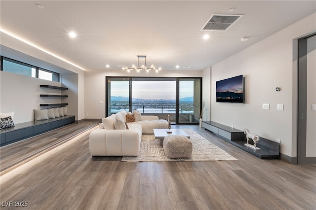 living room featuring an inviting chandelier, baseboards, visible vents, and wood finished floors