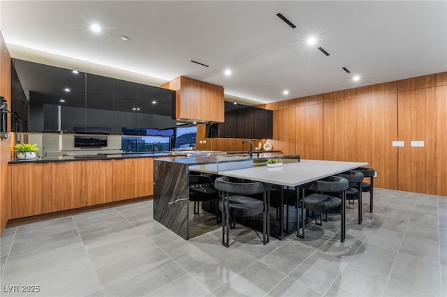 kitchen featuring a large island, modern cabinets, a breakfast bar, and wooden walls