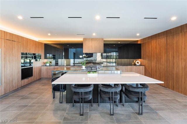 kitchen featuring a breakfast bar, a spacious island, modern cabinets, and wooden walls