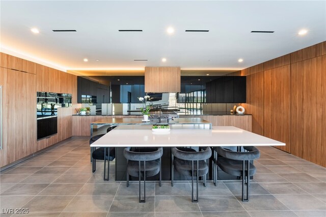 kitchen featuring a kitchen bar, wooden walls, modern cabinets, and a spacious island