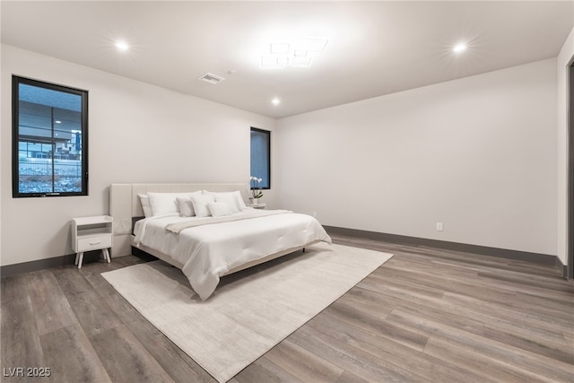 bedroom with baseboards, wood finished floors, and recessed lighting