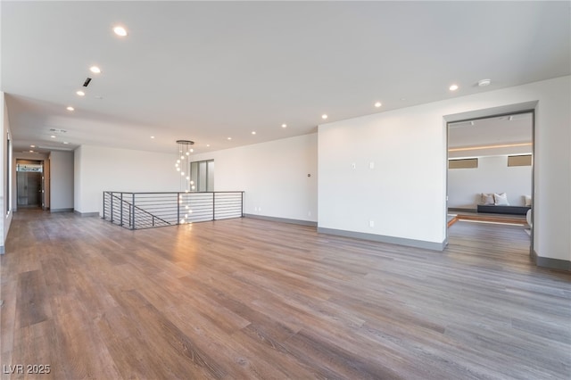 spare room with baseboards, wood finished floors, and recessed lighting