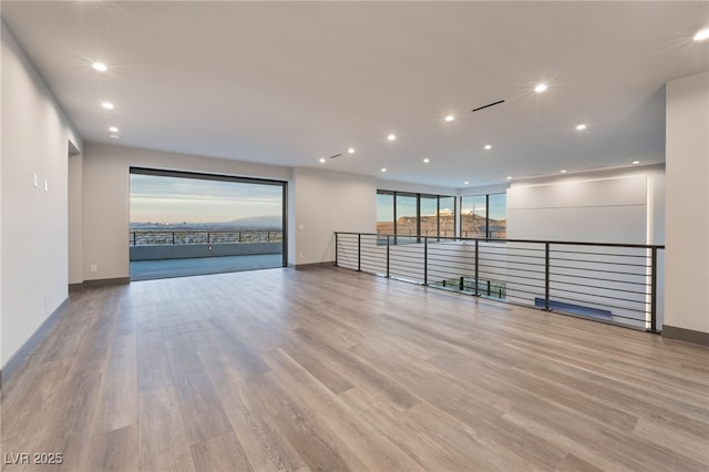 spare room with baseboards, wood finished floors, and recessed lighting