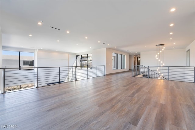 unfurnished room with recessed lighting, an inviting chandelier, and wood finished floors