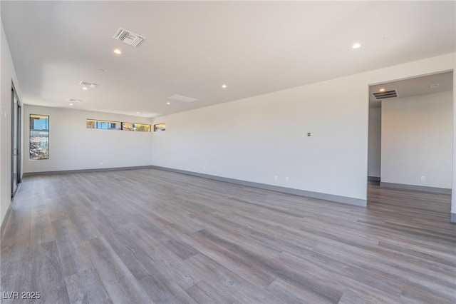 spare room featuring baseboards, visible vents, and wood finished floors