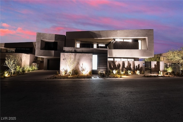 contemporary home with driveway, fence, and stucco siding